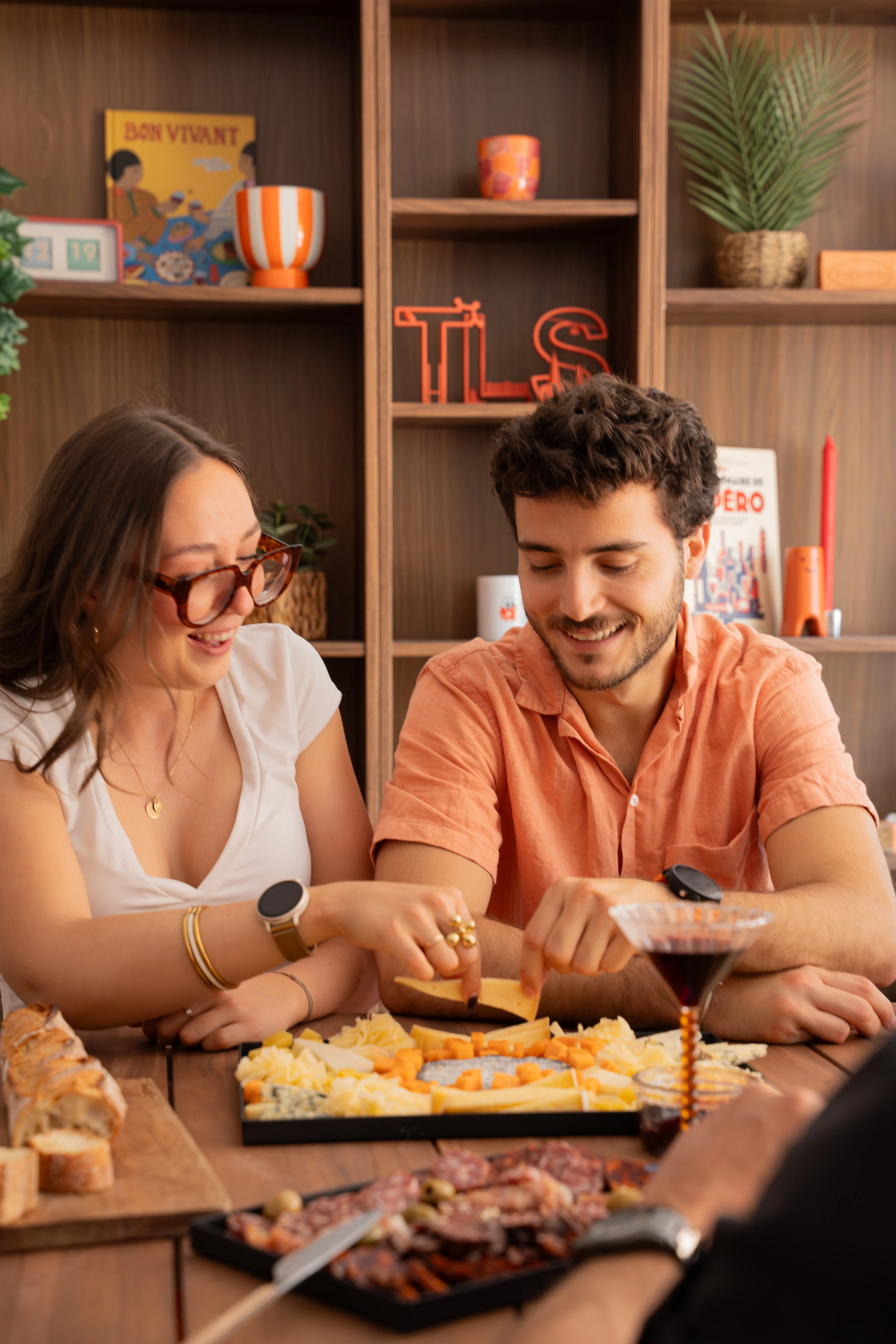 Couple souriant partageant une planche de fromages et charcuteries